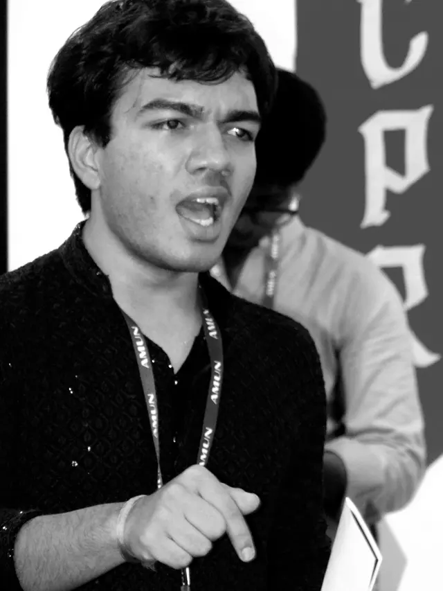 A delegate mid-speech, pointing to land the argument.