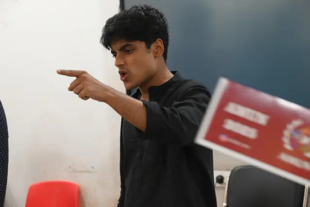 A delegate points across the room during debate.