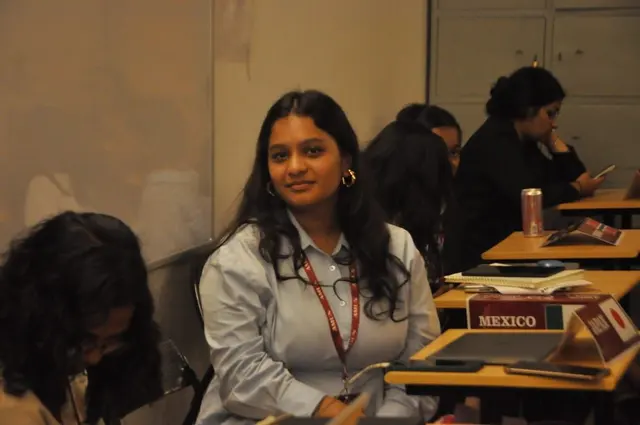 A delegate smiles from behind Mexico’s placard.